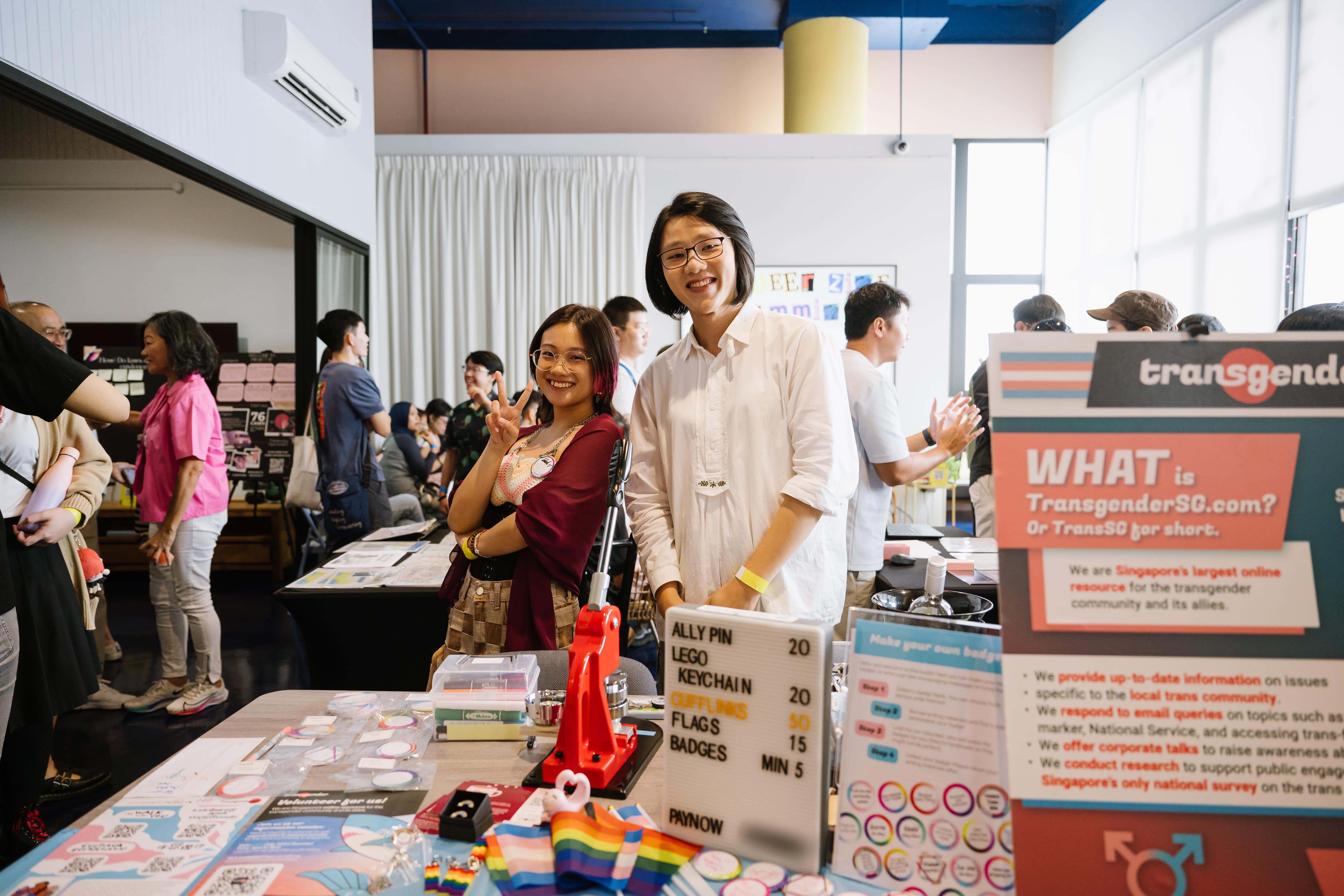 Volunteers smiling and posing behind a TransgenderSG booth at an event